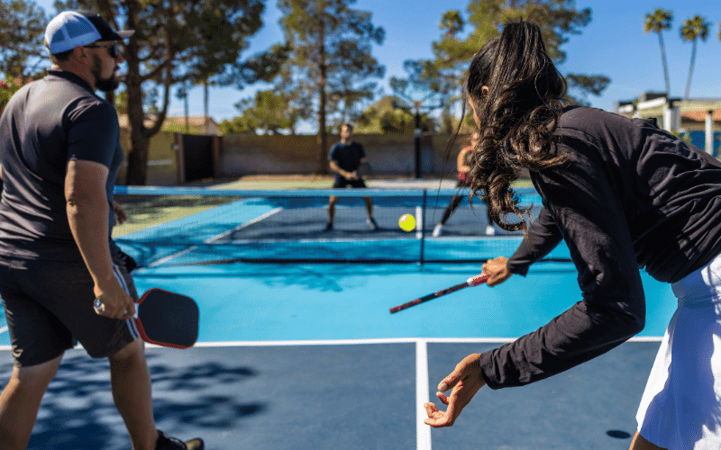 A group of people playing pickleball on a well-maintained court, using proper equipment and techniques to prevent injuries and promote long-term health