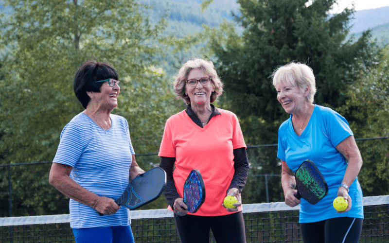 A group of seniors play pickleball on a well-maintained court, using proper form and equipment to minimize the risk of injury